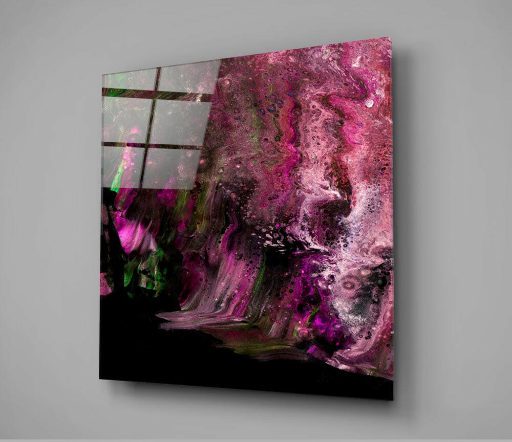 Angled view of square glass wall art displaying vibrant magenta and black flowing abstract patterns with green accents and a grid overlay.
