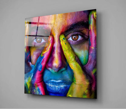 Vibrant multicolored glass wall art featuring a painted face with rainbow hues, mounted on gray wall showing frontal perspective.