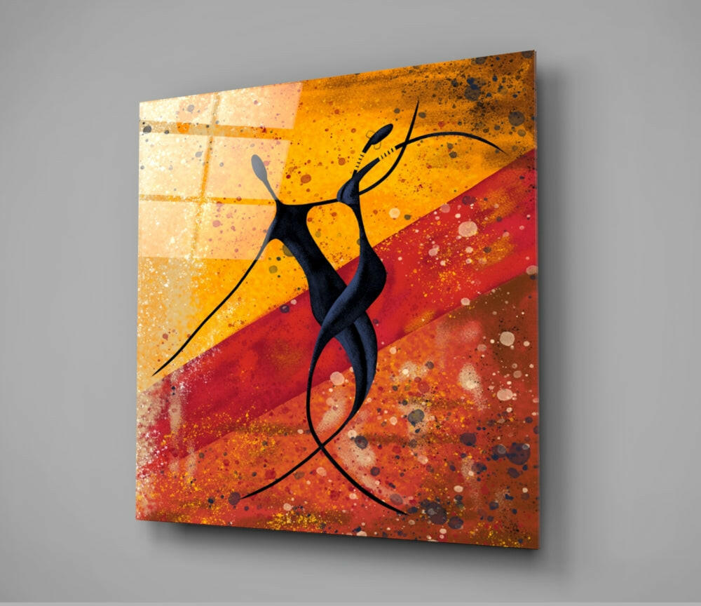 Glass wall art featuring a stylized black dancing figure against warm orange, yellow, and red splattered background with geometric grid pattern.