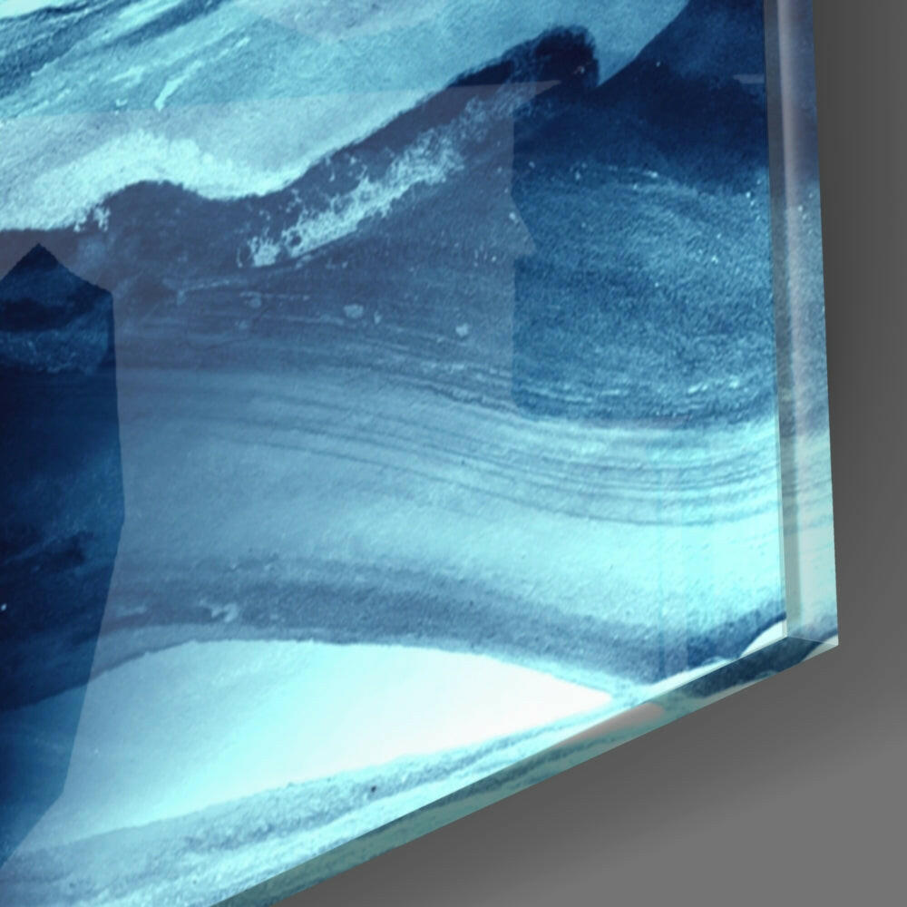 Close-up edge view of glass wall art showing layered blue and white abstract wave patterns with visible glass thickness and gray wall background.