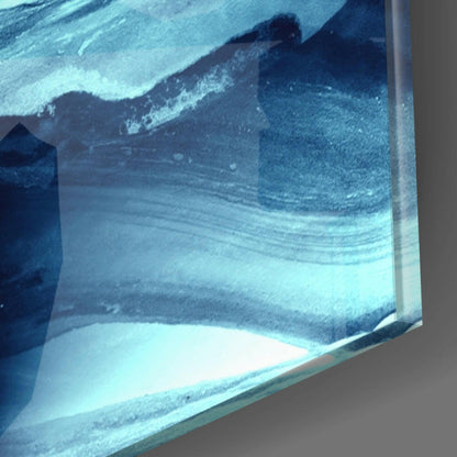 Close-up edge view of glass wall art showing layered blue and white abstract wave patterns with visible glass thickness and gray wall background.