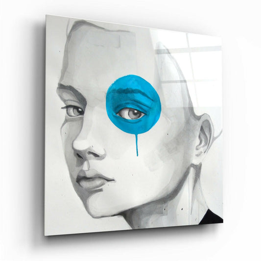 Glass wall art featuring a grayscale portrait with a bright blue circular overlay covering one eye, dripping downward.
