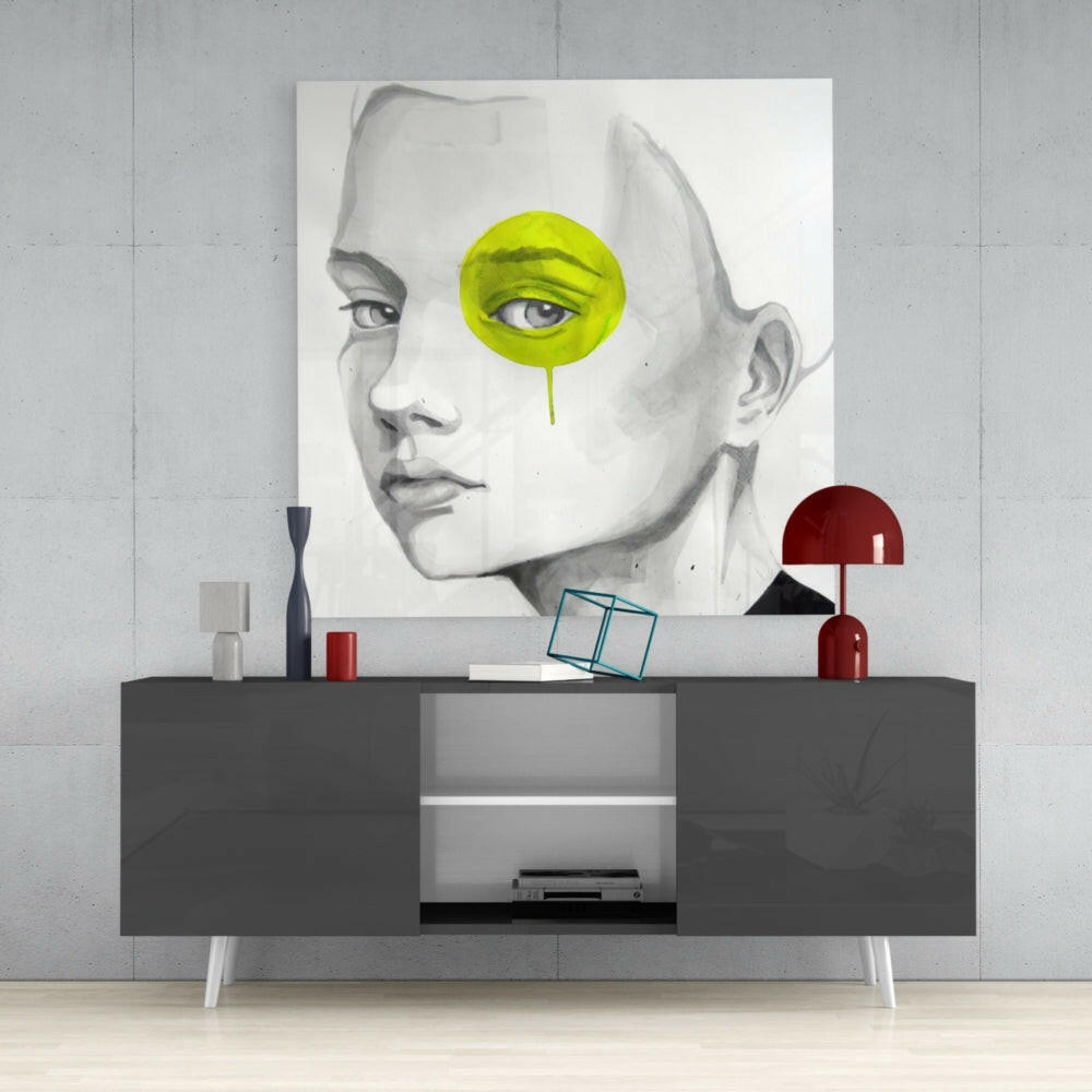 Modern bedroom styling with Yellow Look Glass Wall Art displayed above a gray media console, featuring a pencil-drawn face portrait with lime-green circular eye accent and dripping detail.