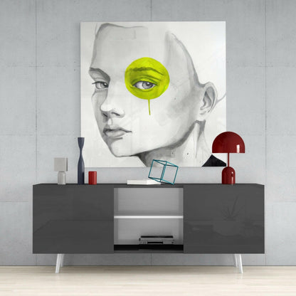 Modern bedroom styling with Yellow Look Glass Wall Art displayed above a gray media console, featuring a pencil-drawn face portrait with lime-green circular eye accent and dripping detail.