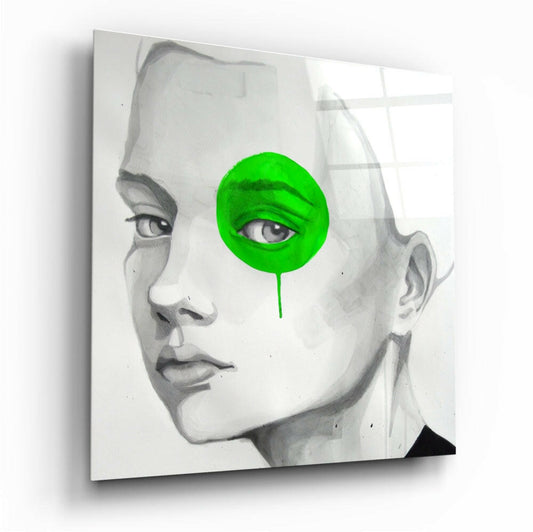 Angled view of glass wall art featuring grayscale portrait with bright green circle covering one eye and dripping paint effect.