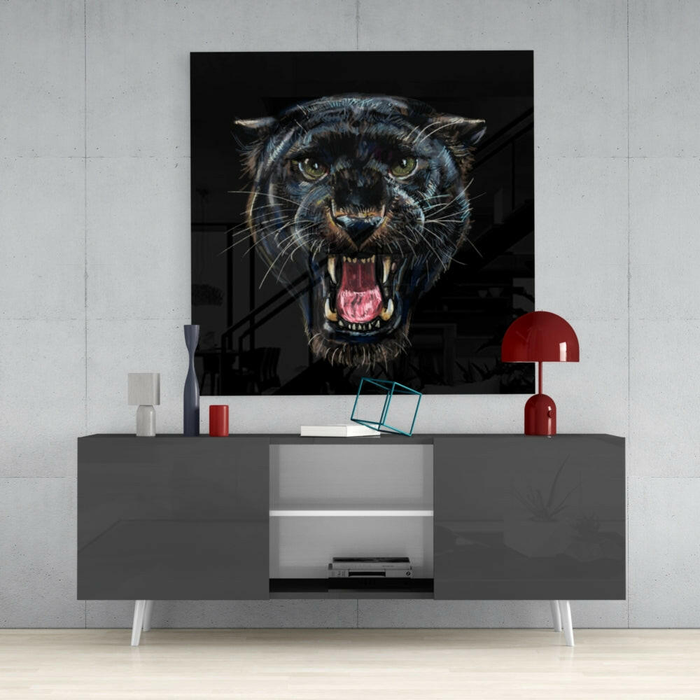Black jaguar glass wall art displaying aggressive snarling face with pink mouth mounted above gray media console with red accents.