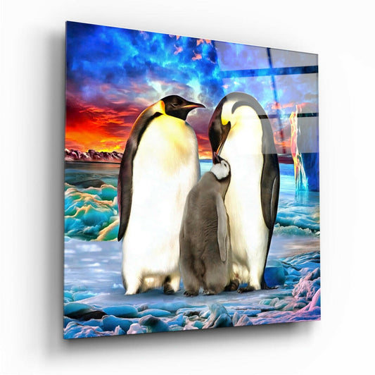 Glass wall art panel displaying two adult penguins with a chick on icy terrain against a dramatic sunset sky backdrop.