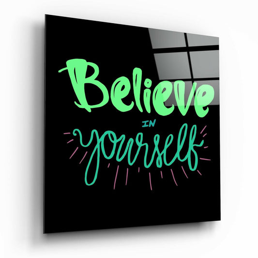 Angled perspective of black glass panel displaying neon green and teal "Believe in Yourself" text with pink decorative lines.