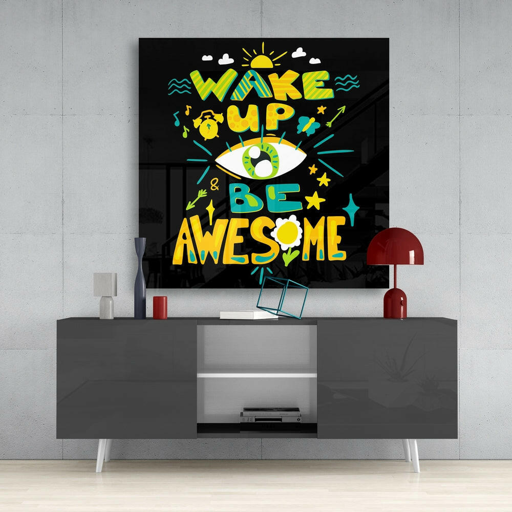 Colorful "Wake Up & Be Awesome" glass wall art with yellow, green, and teal text and illustrations displayed above a gray media console.