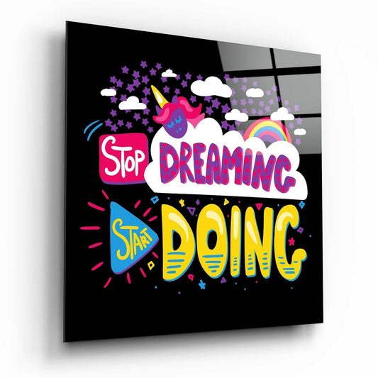 Black glass wall art panel featuring "Stop Dreaming Start Doing" text in bright pink, yellow, and blue with unicorn and rainbow graphics at an angled perspective.