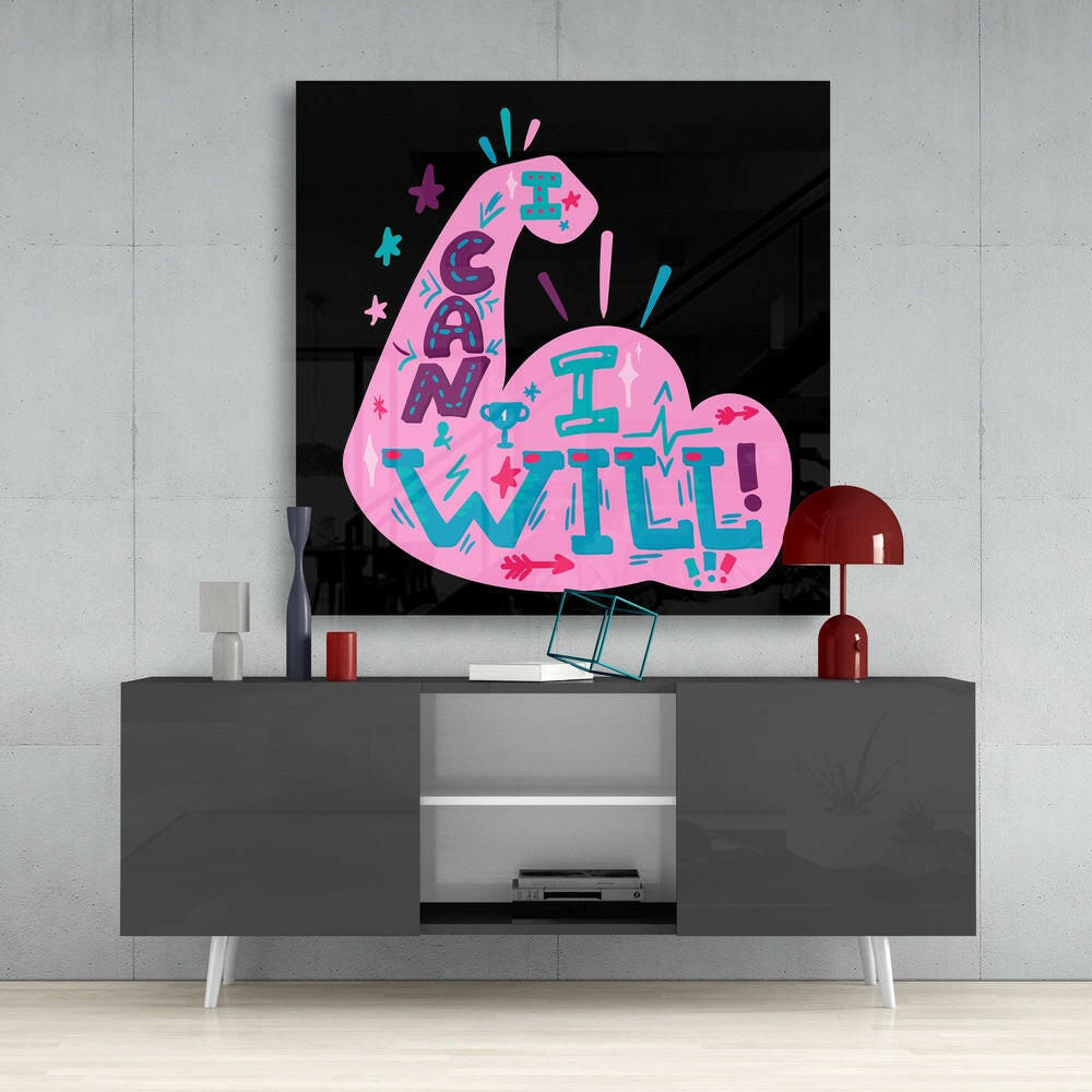 Pink and teal glass wall art displaying "I Can I Will" text mounted above gray media console in modern interior setting.