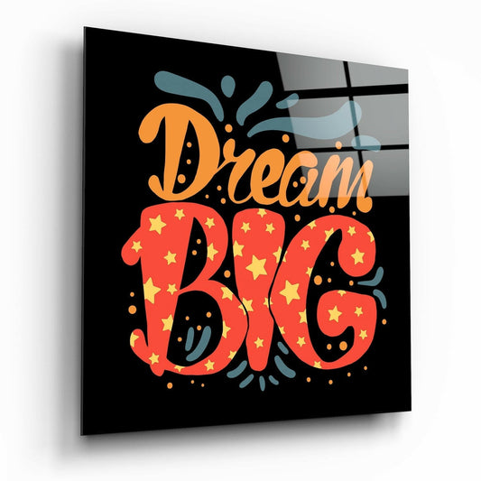 Angled perspective view of glass wall art with orange "Dream" text and red star-patterned "Big" lettering against black background.