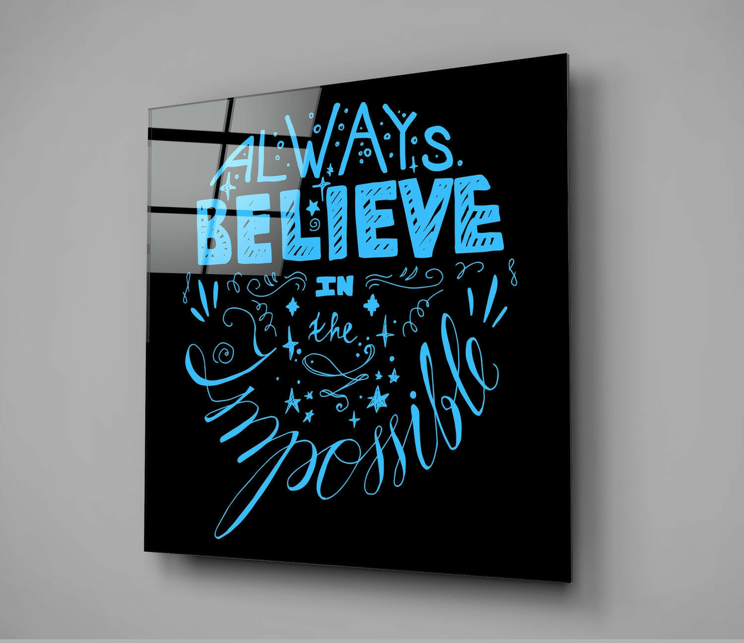 Black glass wall art panel with blue neon-style text reading "Always Believe in the Impossible" displayed at an angle against gray background.