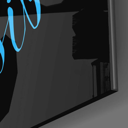 Close-up angled view of blue neon script glass wall art installed on dark gray wall, showing curved lettering and mounting hardware.