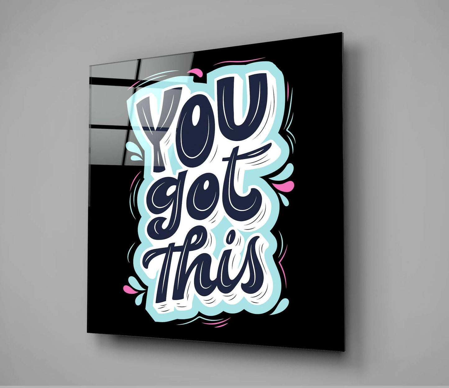 Angled view of glass wall art with navy lettering reading "You Got This" on black background, light blue cloud border and pink accents.