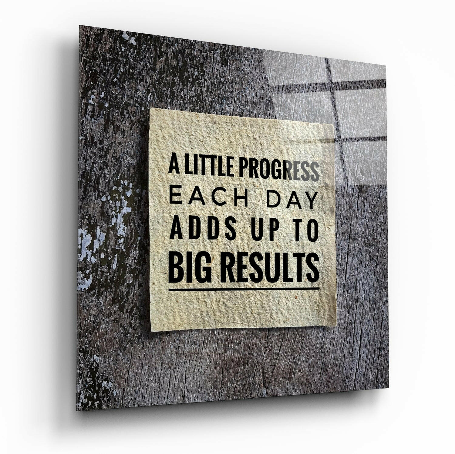 Glass wall art displaying motivational text on cream paper against weathered gray wood background, angled perspective view.