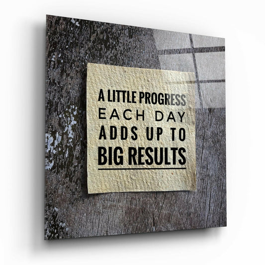 Glass wall art displaying motivational text on cream paper against weathered gray wood background, angled perspective view.