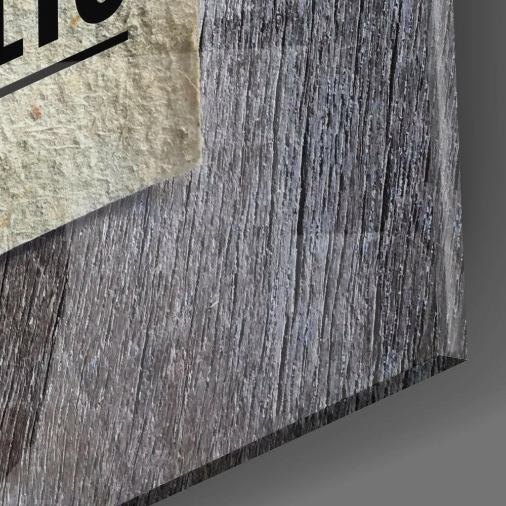 Close-up detail of textured gray wood-grain surface with concrete edge and partial black text visible at top left.