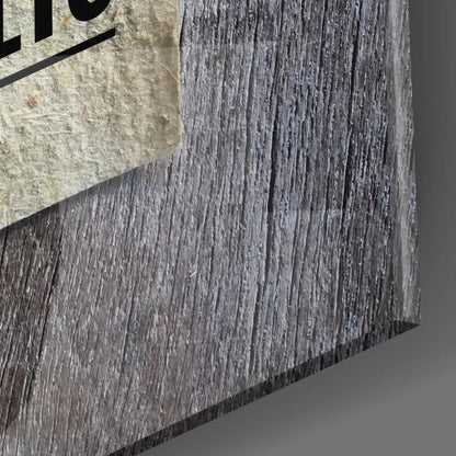 Close-up detail of textured gray wood-grain surface with concrete edge and partial black text visible at top left.