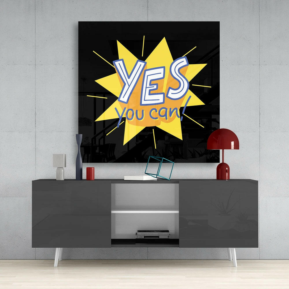 Yes, You Can" motivational glass wall art with yellow star burst and white text displayed above gray media console in modern interior setting.