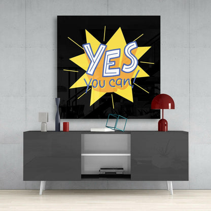 Yes, You Can" motivational glass wall art with yellow star burst and white text displayed above gray media console in modern interior setting.