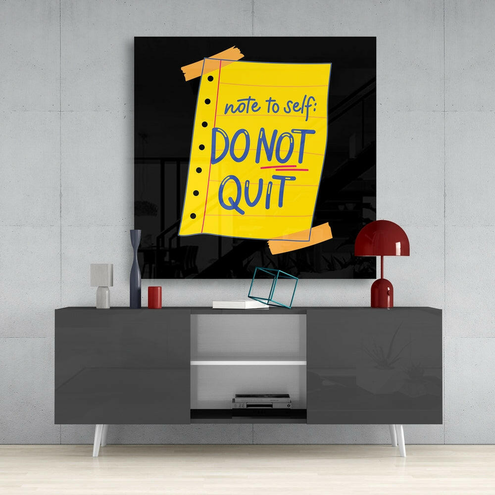 Yellow sticky note glass wall art displaying "note to self: DO NOT QUIT" mounted above gray media console in modern interior setting.