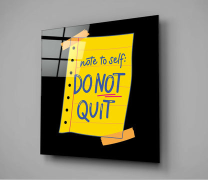 Black glass wall art displaying a yellow lined notepad with blue text reading "note to self: DO NOT QUIT" and orange tape corners, angled perspective view.