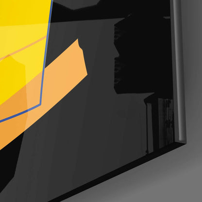 Close-up angled view of glass wall art with yellow and orange geometric shapes and blue border detail against dark background.