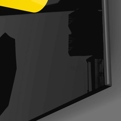 Close-up detail of black glass panel with yellow accent and metallic edge against gray background.