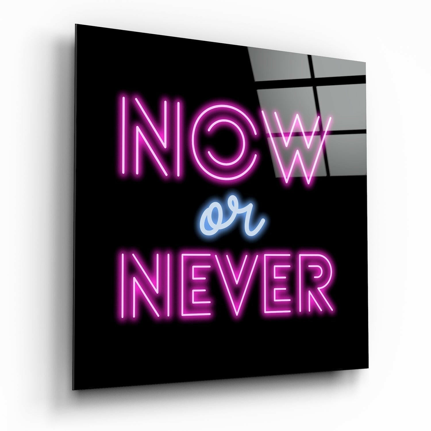 Angled perspective view of black glass wall art displaying pink neon "NOW or NEVER" text with blue "or" against dark background.