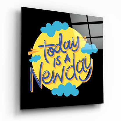 Glass wall art panel displaying "Today is a New Day" text in blue lettering on yellow circle with blue clouds against black background.