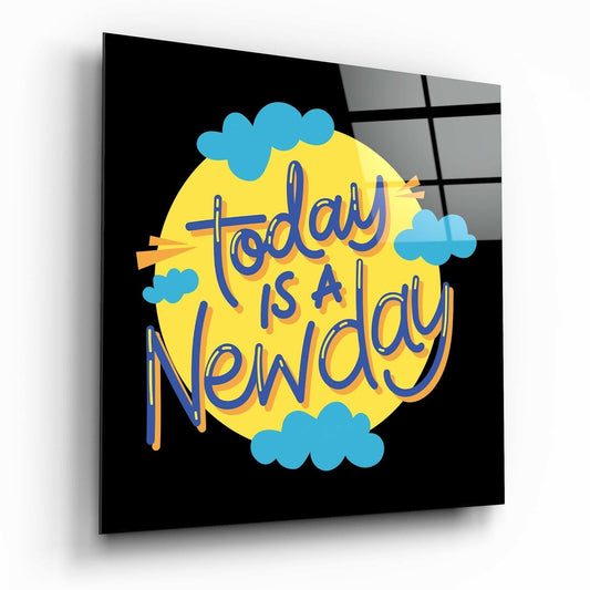 Glass wall art panel displaying "Today is a New Day" text in blue lettering on yellow circle with blue clouds against black background.