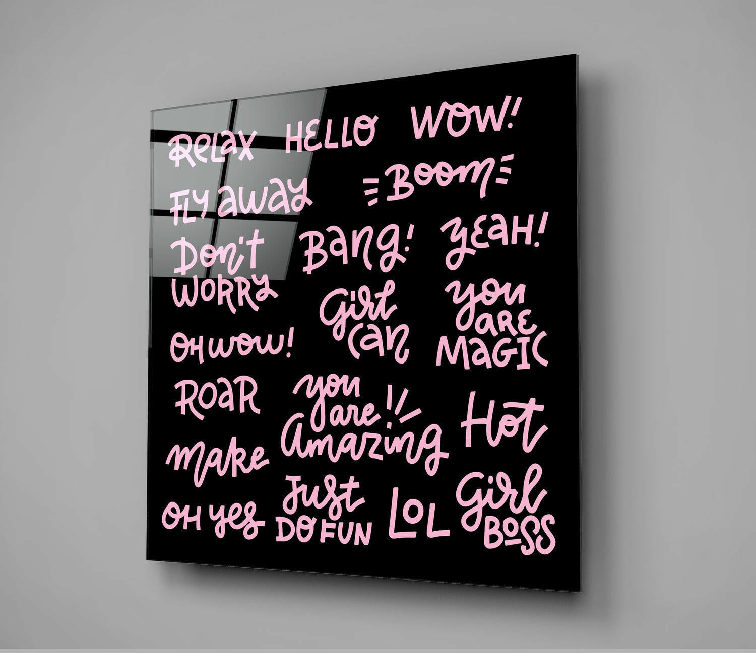 Black glass wall art panel with pink neon-style text displaying empowering phrases like "Girl Boss," "You Are Magic," and "Relax," mounted at an angle against gray wall.