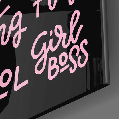 Close-up angled view of black glass wall art with pink cursive text reading "Girl Boss" and partial text above and below.