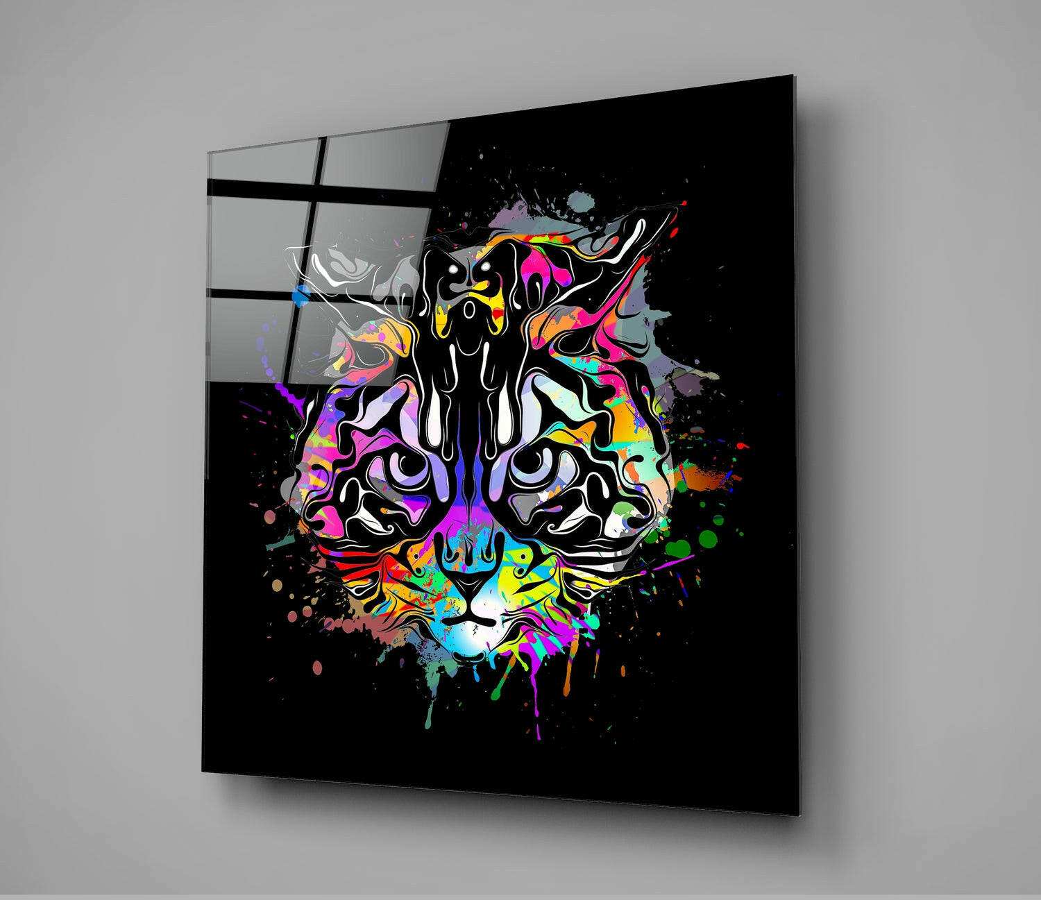 Colorful neon cat face with paint splatters on black glass panel mounted on gray wall, angled perspective view.