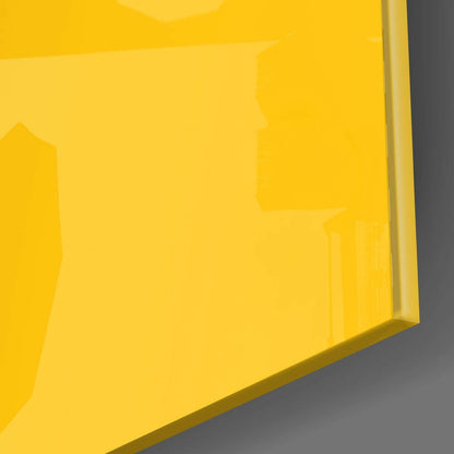 Angled close-up of bright yellow custom glass wall art panel showing beveled edge against gray background.
