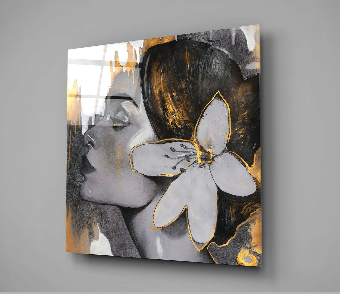 Square glass wall art featuring a woman's profile with dark hair and white flower with gold accents against black and gold background.