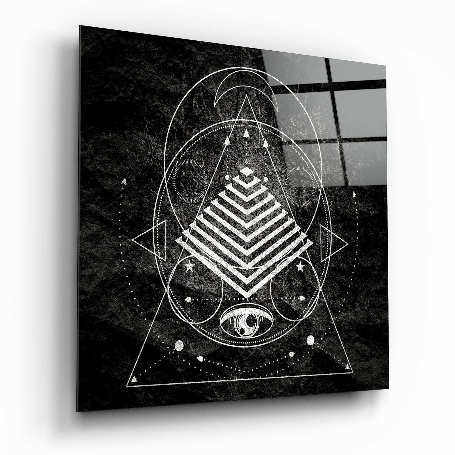 Black and white geometric sacred geometry design on glass with pyramid, circles, triangles, and eye symbol on textured background.