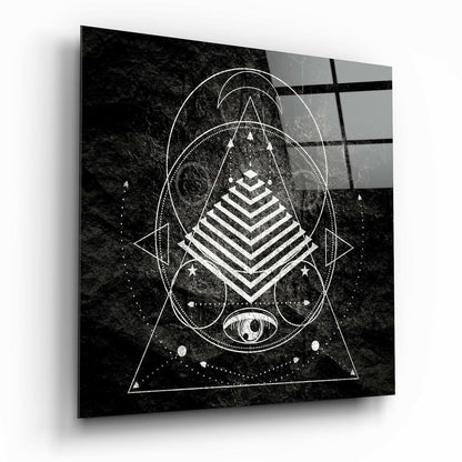 Black and white geometric sacred geometry design on glass with pyramid, circles, triangles, and eye symbol on textured background.