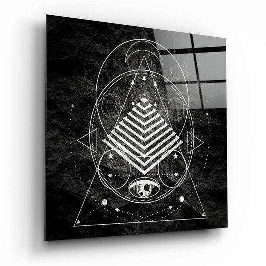 Black and white geometric sacred geometry design on glass with pyramid, circles, triangles, and eye symbol on textured background.