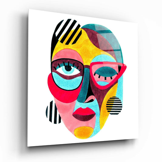 Angled view of a glass wall art panel displaying a vibrant cubist portrait with yellow, pink, turquoise, and black geometric sections.
