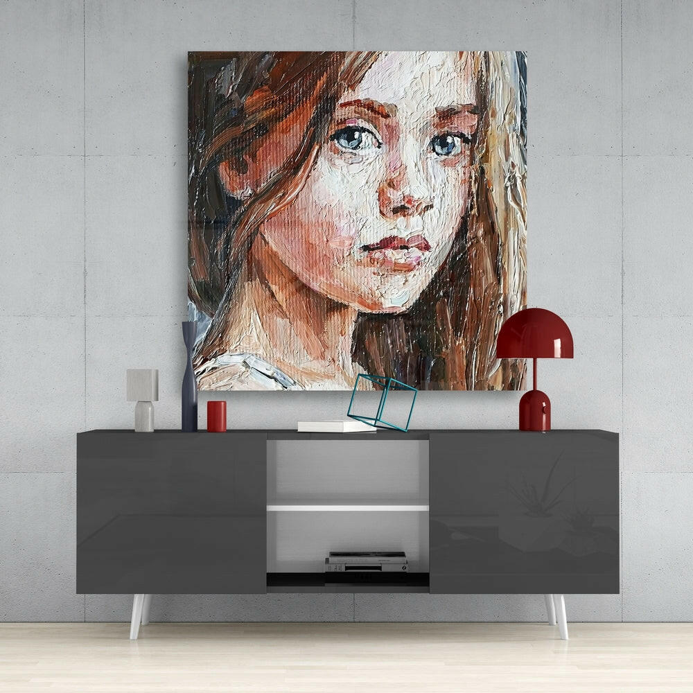 Portrait painting of a girl with blue eyes and long brown hair displayed above a gray modern sideboard with red decorative items.