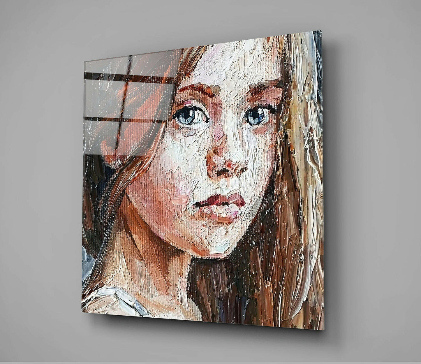 Square glass wall art displaying an expressive painted portrait of a girl with brown hair and blue eyes, mounted on gray wall.