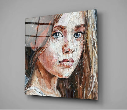 Square glass wall art displaying an expressive painted portrait of a girl with brown hair and blue eyes, mounted on gray wall.
