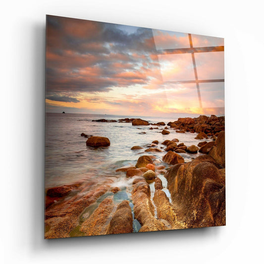 Rocky coastline at sunset with golden light reflecting through a window grid overlay on glass wall art.