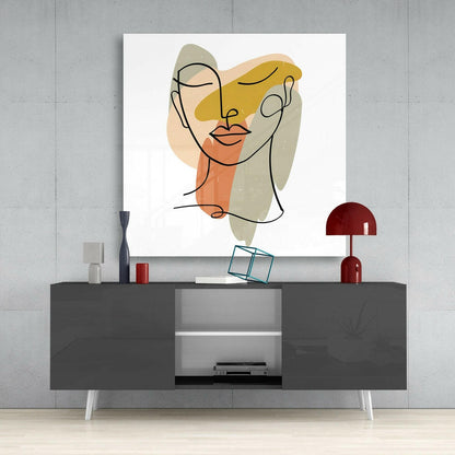 Abstract line-drawn face with yellow, orange, and beige watercolor shapes displayed above modern gray console table with red lamp.