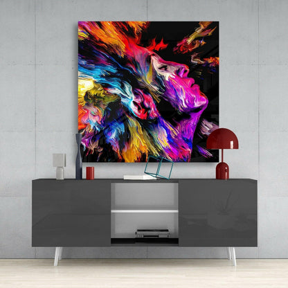 Vibrant multicolored abstract lion portrait glass art displayed above gray media console with red lamp and accessories.