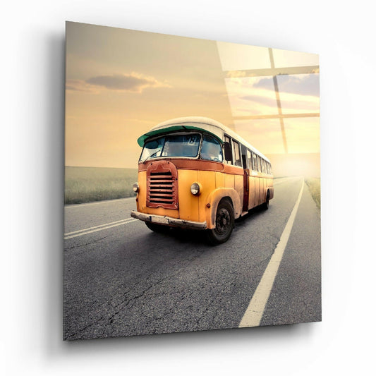 Vintage orange and green bus driving on a straight highway at sunset with flat landscape and golden sky reflected in glass.