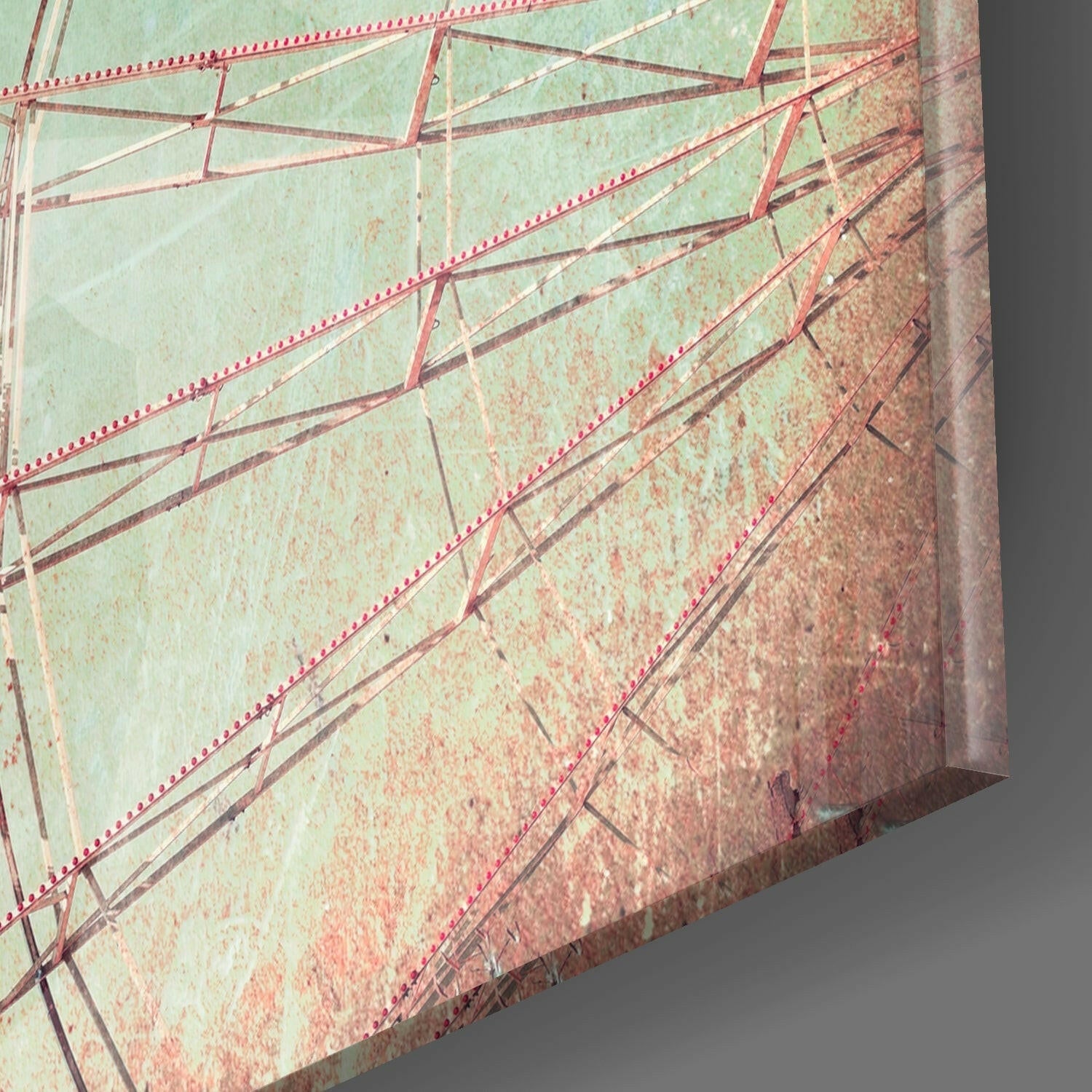 Close-up edge view of glass wall art showing layered mint green and rust-toned glass with red rivets and metal framework details.