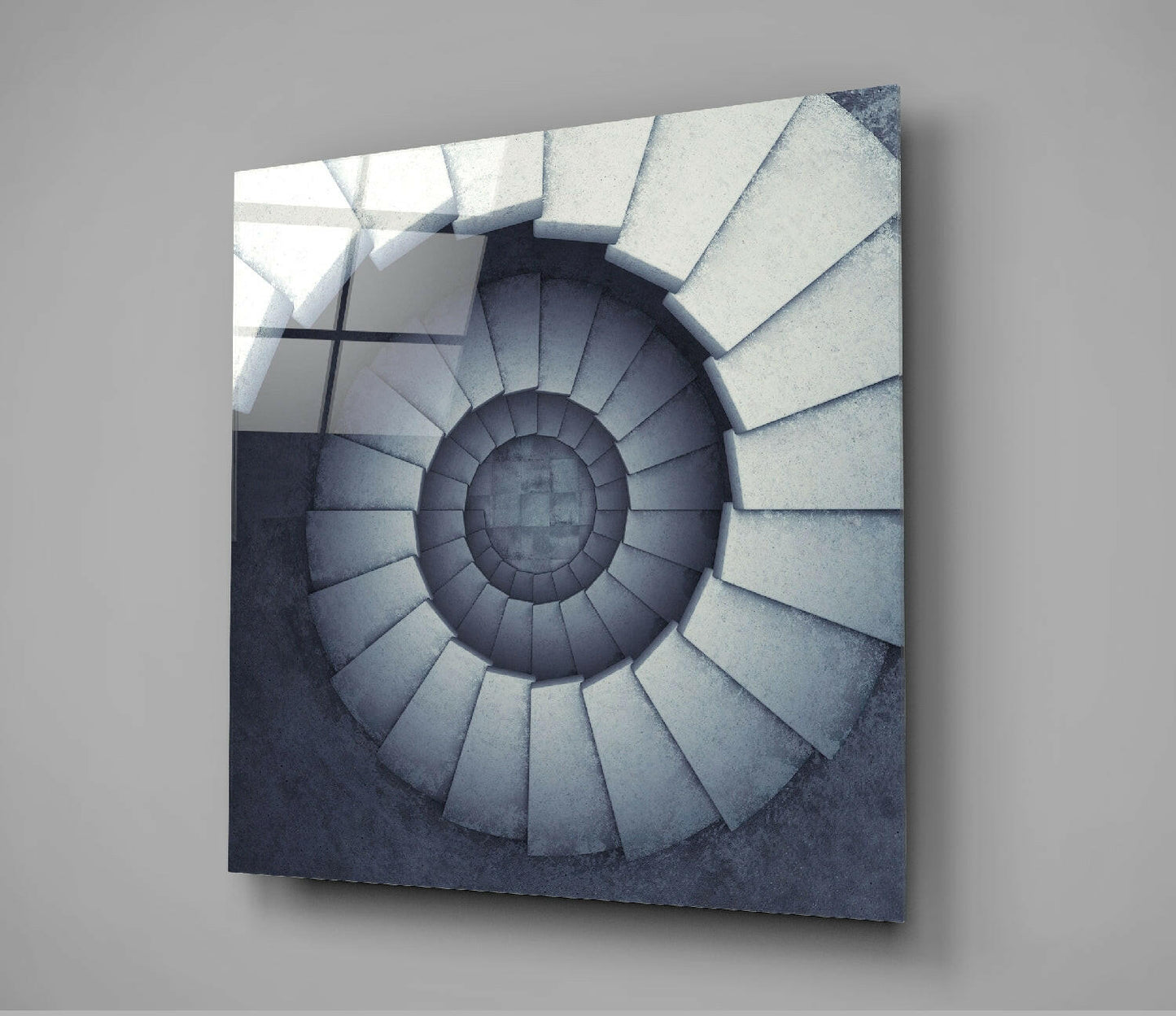 Square glass panel displaying a spiral staircase descending into shadow, rendered in grayscale tones, mounted on gray wall.